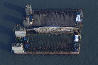 Workers try to raise the sunken Sewol ferry, center, between two barges during the salvage operation in waters off Jindo, South Korea, Thursday, March 23, 2017. The 6,800-ton South Korean ferry emerged from the water on Thursday, nearly three years after it capsized and sank into violent seas off the country's southwestern coast, an emotional moment for the country that continues to search for closure to one of its deadliest disasters ever. (Gang Jong-min/Newsis via AP)