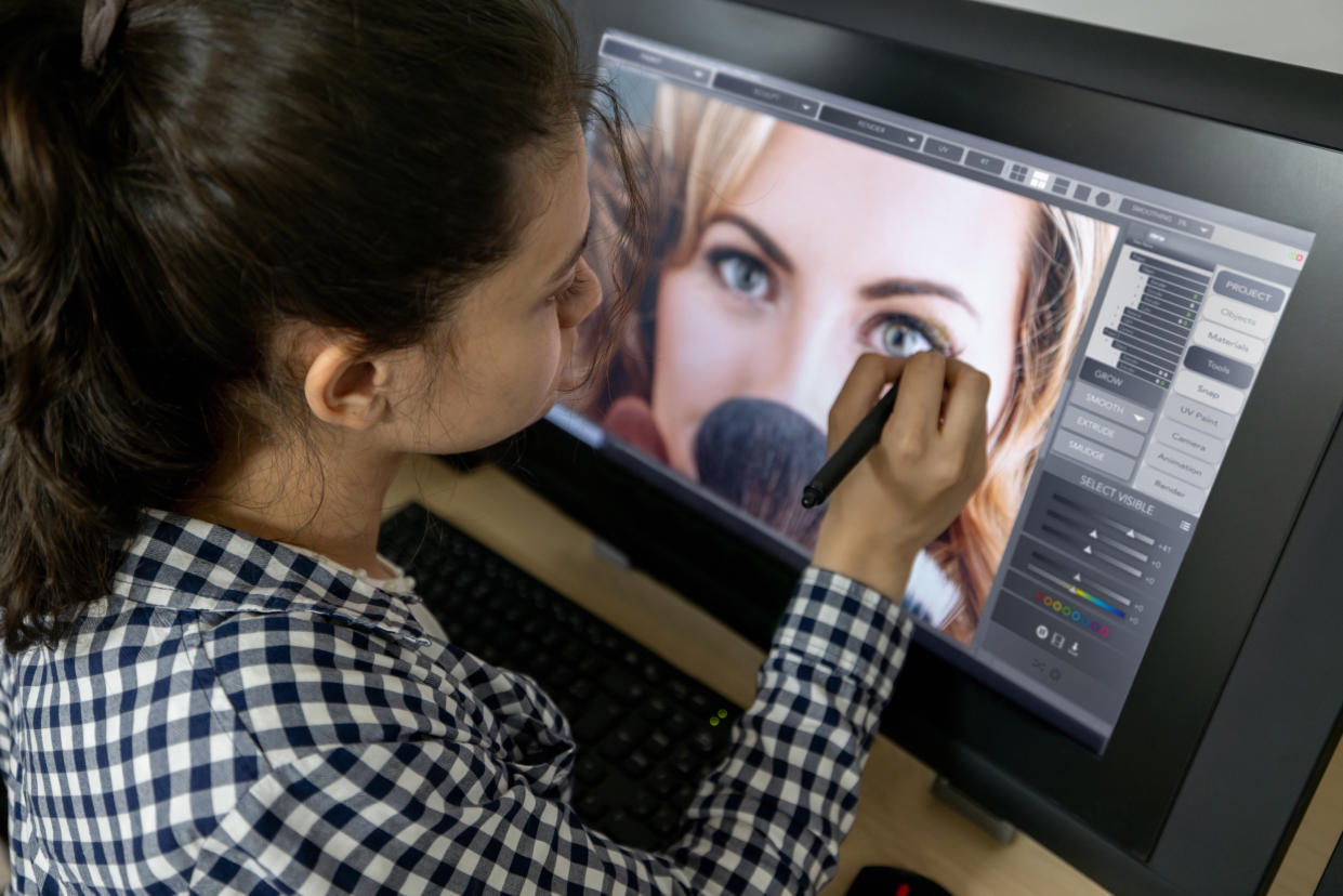 College student retouching a photo in an editing class using a computer and a stylus pen - IT education concepts