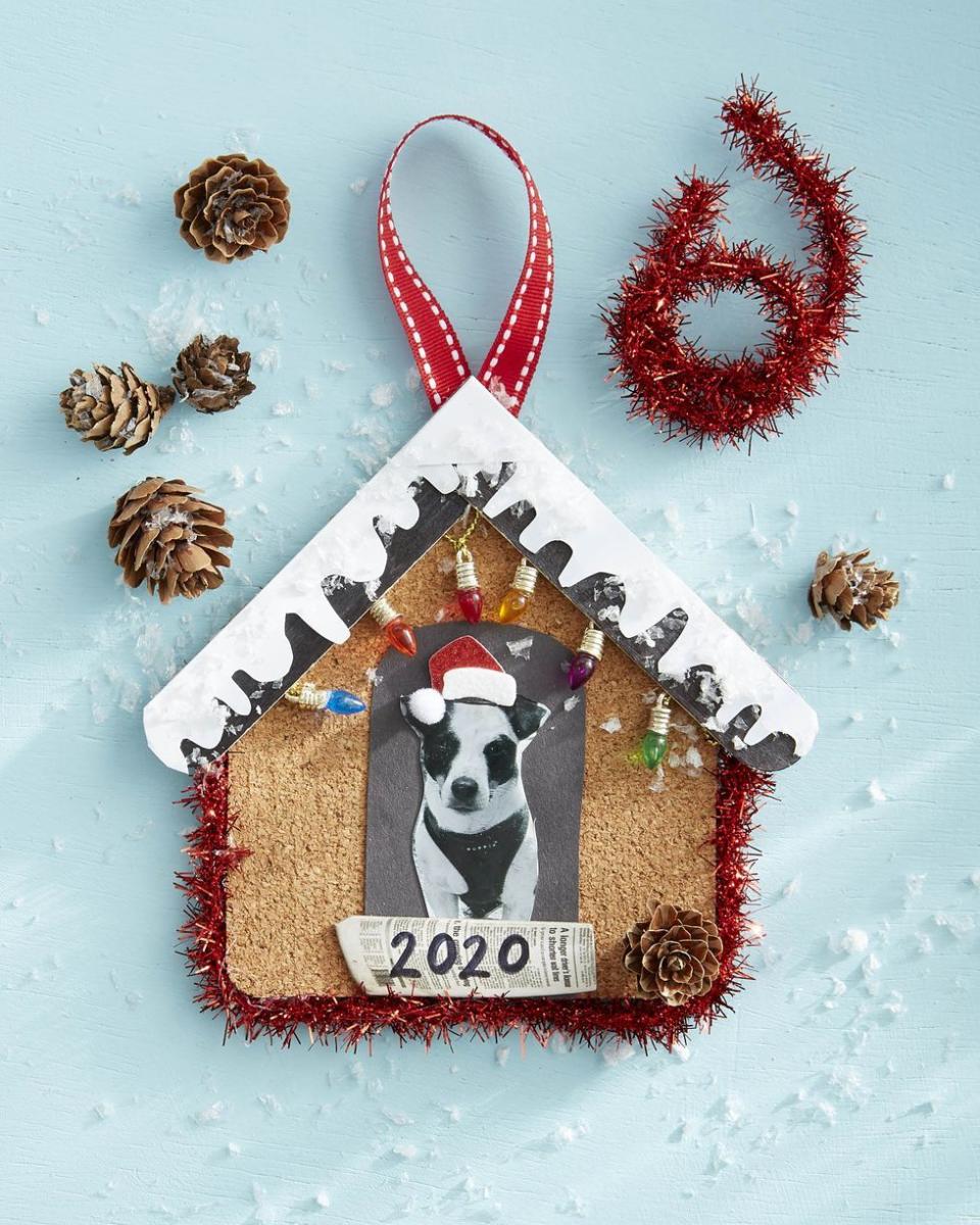 ornament made to look like a doghouse with snow on top and small christmas lights, with a picture of a dog in the doghouse