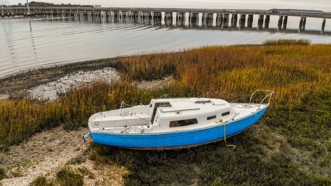 An abandoned boat rests at low tide on the mud flats of Mackay Creek as traffic moves over the Karl S. Bowers Bridge on U.S. 278 on Dec. 6, 2022 one of two bridges that connects the mainland to Hilton Head Island.