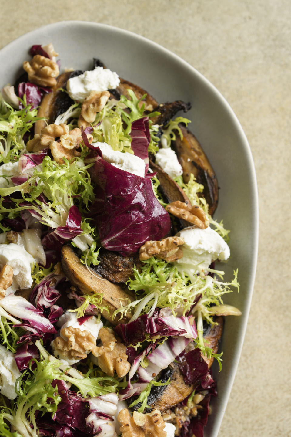 This image released by Milk Street shows a recipe for frisée and mushroom salad with goat cheese and walnuts. (Milk Street via AP)