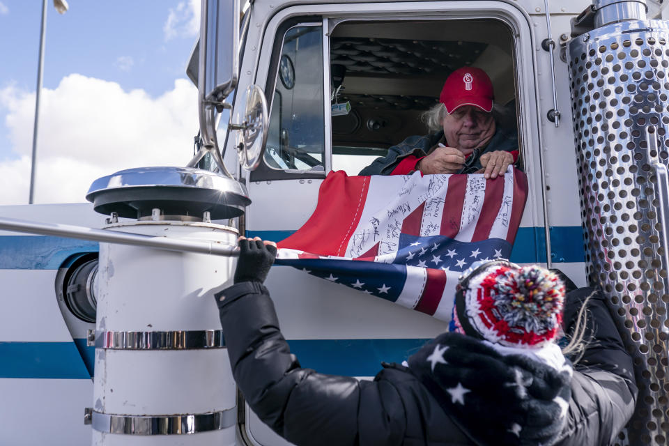 A truck driver signs an American flag at the beginning of a trucker caravan to Washington, D.C., called The People's Convoy on Wednesday, Feb. 23, 2022, in Adelanto, Calif. A small convoy of truckers demanding an end to coronavirus mandates began a cross-country drive from California to the Washington, D.C., area on Wednesday. (AP Photo/Nathan Howard)
