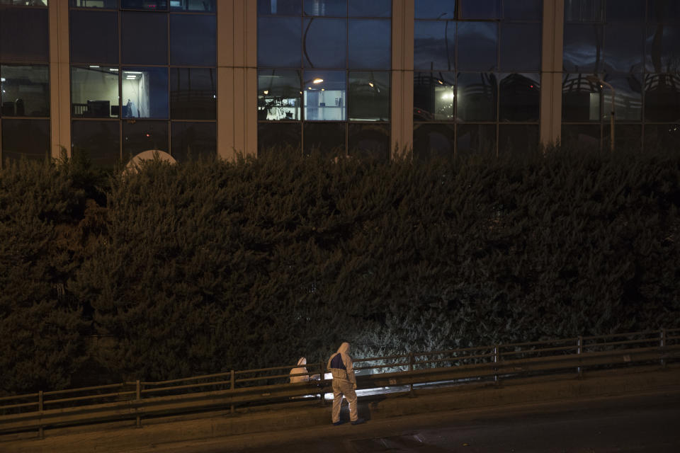 Greek forensic experts search at the scene after a powerful bomb exploded outside private Greek television station, in Faliro, Athens, Monday, Dec, 17, 2018. Police said the blast occurred outside the broadcasters' headquarters near Athens after telephoned warnings prompted authorities to evacuate the building, causing extensive damage but no injuries. (AP Photo/Petros Giannakouris)