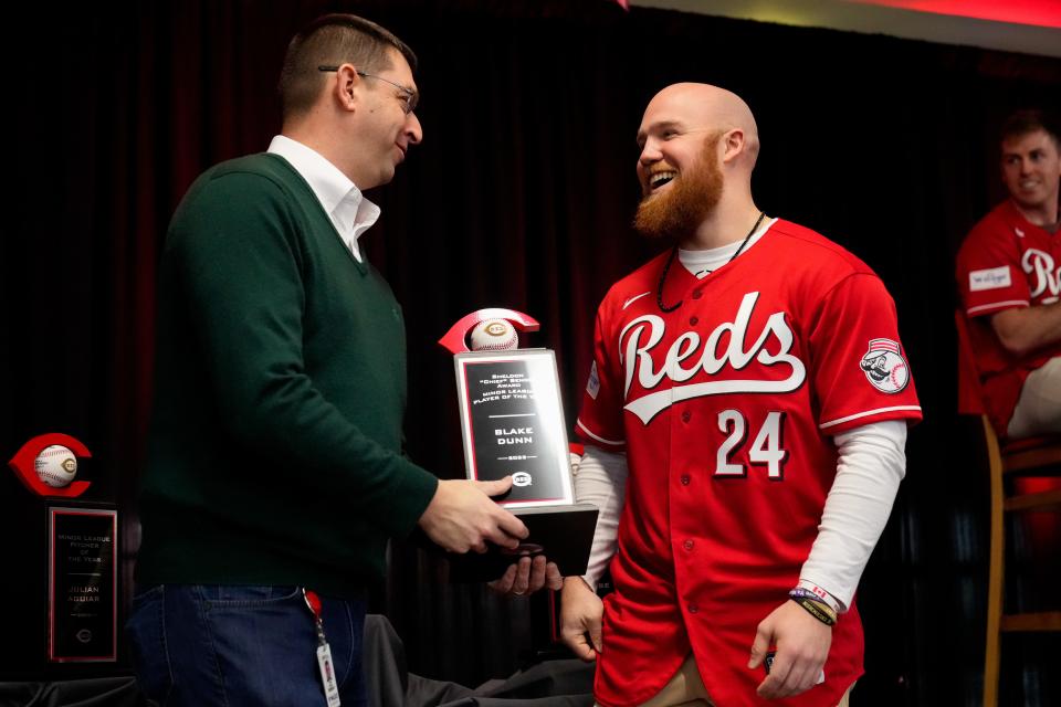 Outfielder Blake Dunn, here receiving the Reds minor league player of the year award from president of baseball operations Nick Krall, is among the young players who will get a chance to show their abilities early in spring training.