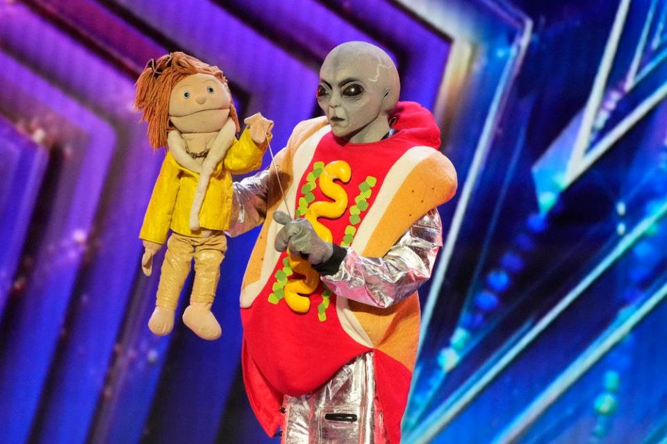 Wearing an alien mask and gloves, paired with a hot dog costume, a ventriloquist unsuccessfully auditioned for the judges with a doll-like puppet named Poose, left.