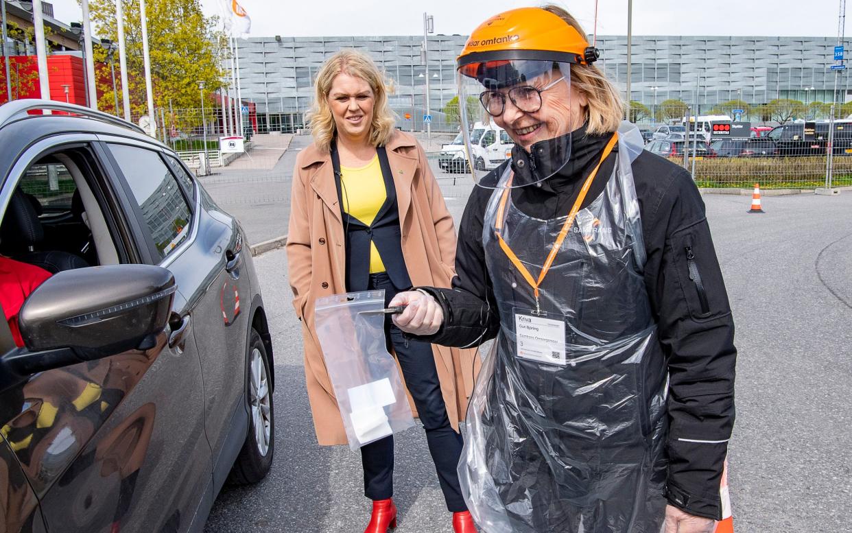 Sweden's Minister for Health and Social Affairs Lena Hallengren (centre of picture) looks on as a health worker administers a Covid-19 test in Stockholm in May - Jonas Ekstromer/AP