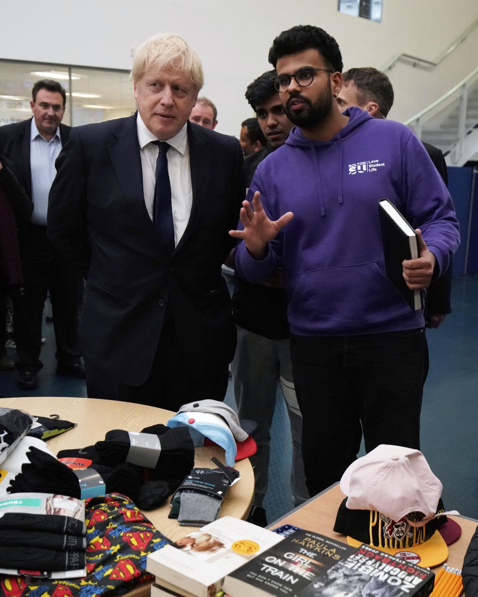 Britain's Prime Minister Boris Johnson, left, views collected goods as he speaks to staff and students at Bolton University, in Bolton, England, Saturday Nov. 16, 2019, in the aftermath of a major blaze which damaged a student residential building late Friday. A large fire broke out in a student accommodation block of flats known as The Cube late Friday, resulting in two people being treated at the scene. Visiting the scene, Johnson broke from his election campaign trail ahead of the Dec. 12 General Election. (Christopher Furlong/pool via AP)