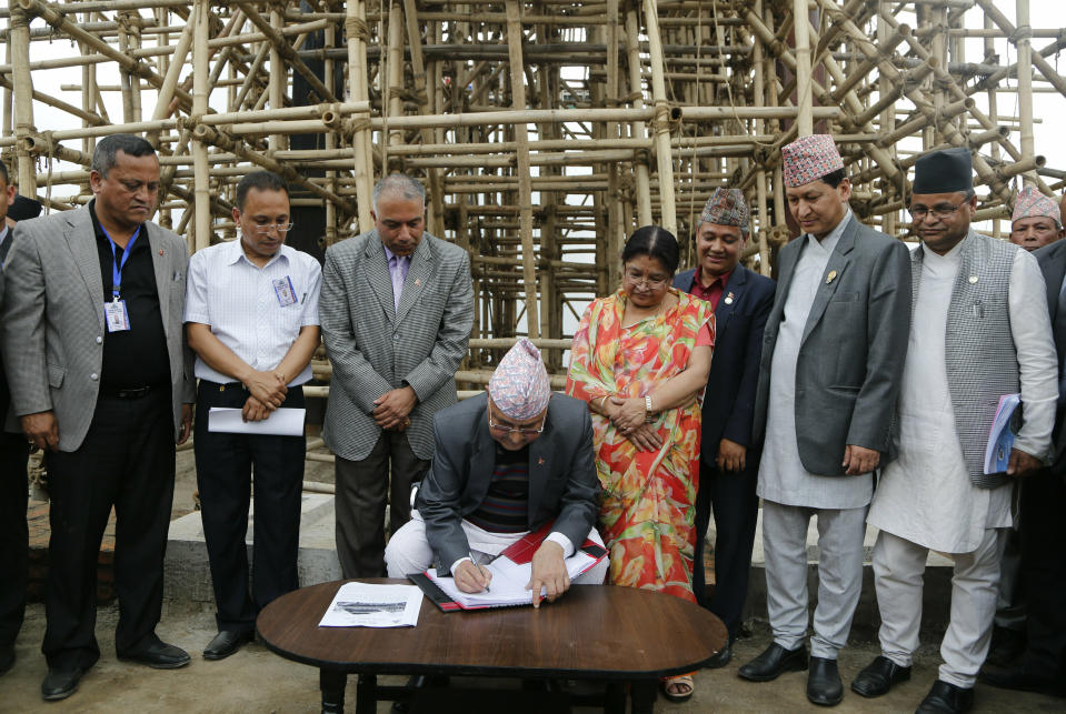 Nepal Prime Minister Khadga Prasad Oli writes his remarks in front of the Kasthamandap temple which collapsed in the 2015 earthquake, during a function to mark the anniversary of the quake in Kathmandu, Nepal, Thursday, April 25, 2019. The violence of the 7.8-magnitude earthquake killed nearly 9,000 people and left countless towns and villages across central Nepal in shambles. (AP Photo/Niranjan Shrestha)