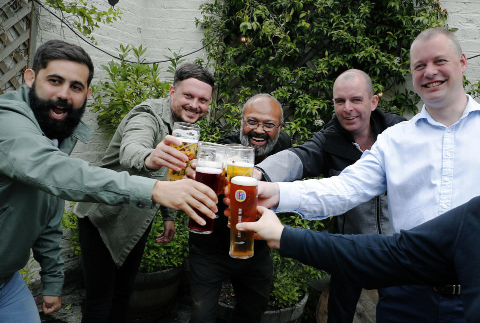 Men enjoy their first beers as the Chandos Arms pub reopens, in London, Saturday, July 4, 2020. England is embarking on perhaps its biggest lockdown easing yet as pubs and restaurants have the right to reopen for the first time in more than three months. In addition to the reopening of much of the hospitality sector, couples can tie the knot once again, while many of those who have had enough of their lockdown hair can finally get a trim. (AP Photo/Frank Augstein)