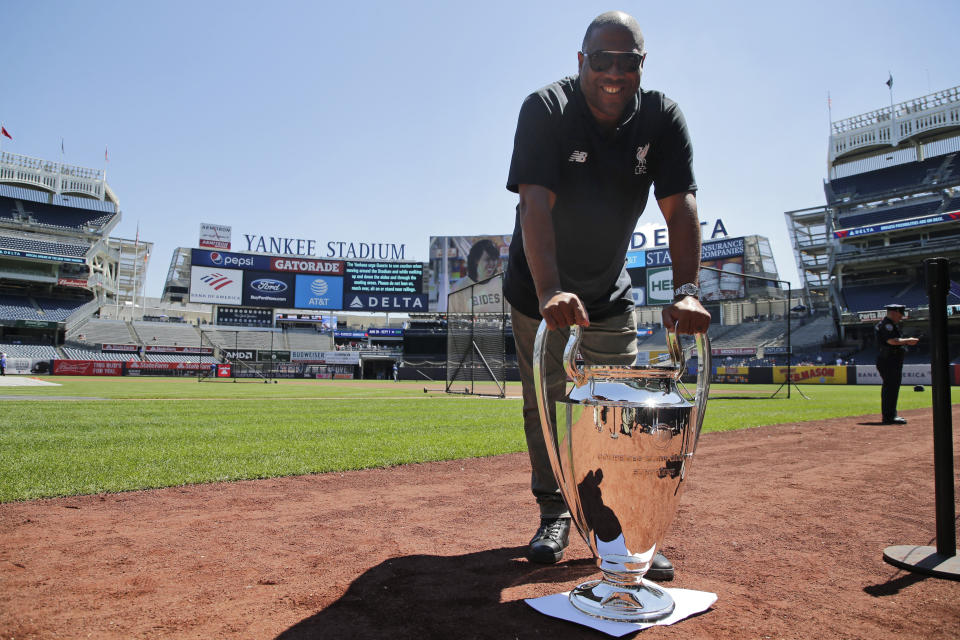 Former Liverpool FC player John Barnes poses for a picture with a replica of the Champions League trophy before a baseball game at Yankee Stadium, Wednesday, June 26, 2019, in New York. Liverpool FC will face Sporting Club of Portugal in a friendly match at Yankee Stadium on July 24, 2019. (AP Photo/Seth Wenig)