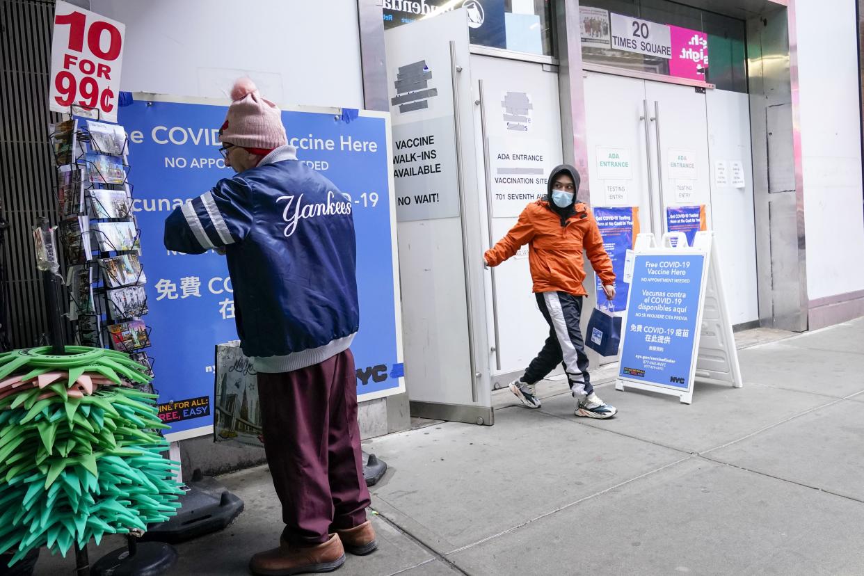 A man, right, leaves the NYC Vaccine Hub in New York's Times Square, Monday, Dec. 6, 2021. 