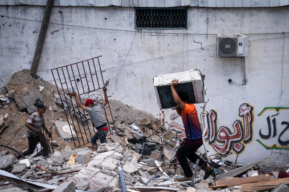 People reclaim valuable materials from a debris pile of a building destroyed by an airstrike prior to a cease-fire reached after an 11-day war between Gaza's Hamas rulers and Israel, in Gaza City, Saturday, May 22, 2021.