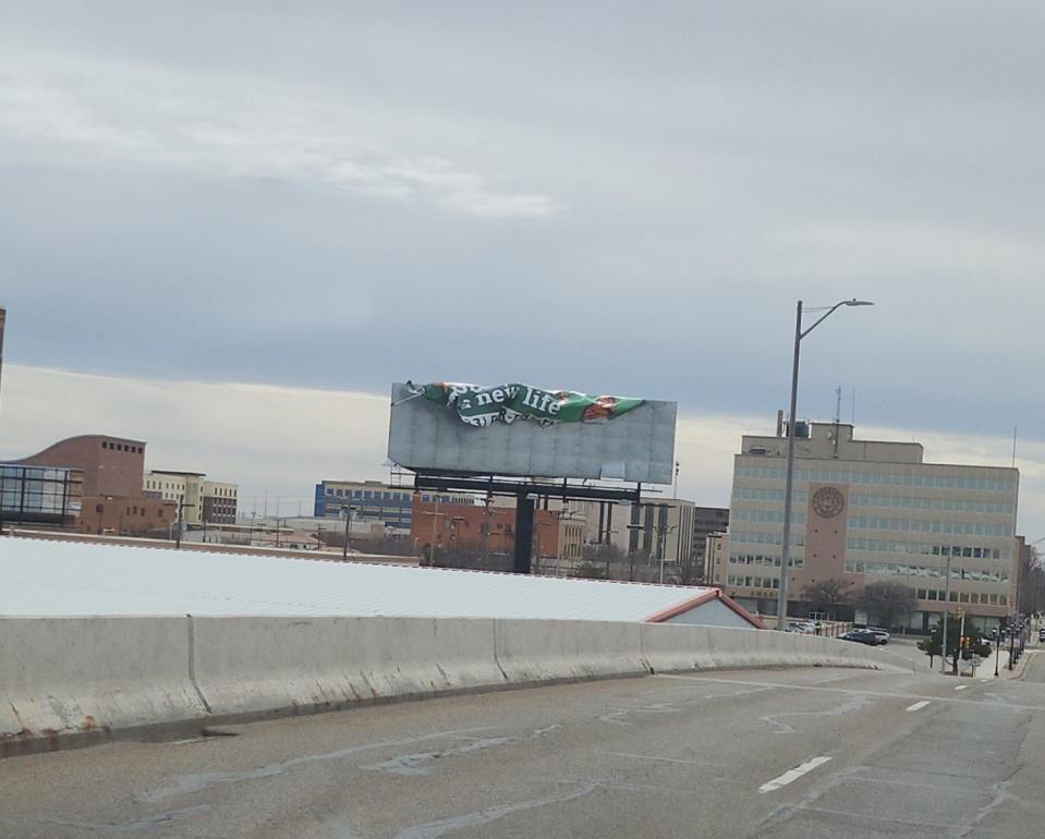 A billboard ad, seen over the Taylor Street bridge leading into downtown Amarillo, flaps in the wind as Amarillo faces high winds Tuesday afternoon.