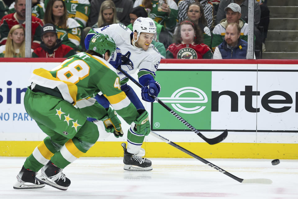 Vancouver Canucks center Teddy Blueger (53) shoots while Minnesota Wild defenseman Daemon Hunt (48) defends during the third period of an NHL hockey game Saturday, Dec. 16, 2023, in St Paul, Minn. (AP Photo/Matt Krohn)