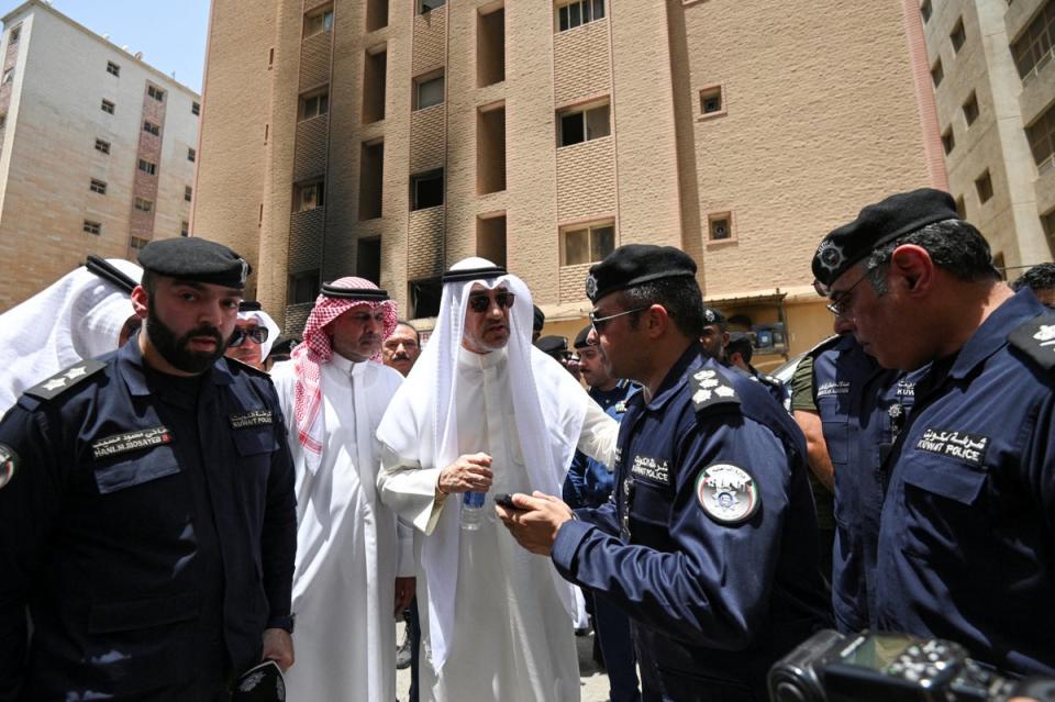 Kuwait's deputy prime minister and Minister of Defense and acting interior minister, Fahad Yusuf Al-Sabah speaks with police officers in front of a burnt building (REUTERS)