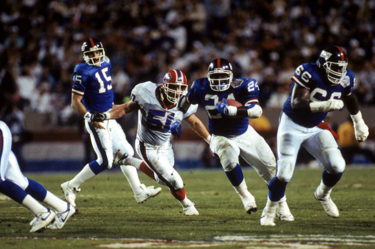 Running back Ottis Anderson #24 of the New York Giants carries the ball as offensive guard William Roberts #66 leads the way while linebacker Ray Bentley #50 of the Buffalo Bills pursues during Super Bowl XXV at Tampa Stadium on January 27, 1991