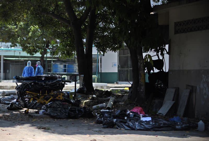 Health workers wearing protective gear are seen behind body bags outside of Teodoro Maldonado Carbo Hospital amid the spread of the coronavirus disease (COVID-19), in Guayaquil