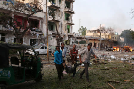 Civilians evacuate an unidentified man injured from the scene of a suicide car bombing outside Hotel Ambassador on Maka Al Mukaram Road in Somalia's capital Mogadishu, June 1, 2016. REUTERS/Feisal Omar