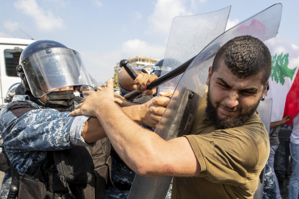 Riot police scuffle with anti-government protesters outside the Ministry of Energy and Water in Beirut, Lebanon, Tuesday, Aug. 4, 2020. Dozens of Lebanese protesters tried to storm the Ministry of Energy on Tuesday, angered by prolonged power cuts as the country grapples with a crippling economic crisis. (AP Photo/Hassan Ammar)