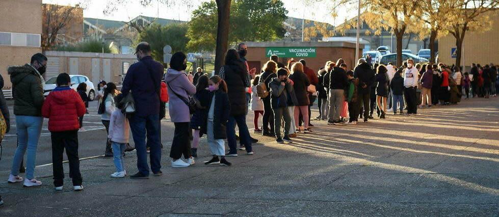 Des Espagnols font la queue pour faire vacciner leurs enfants. 
