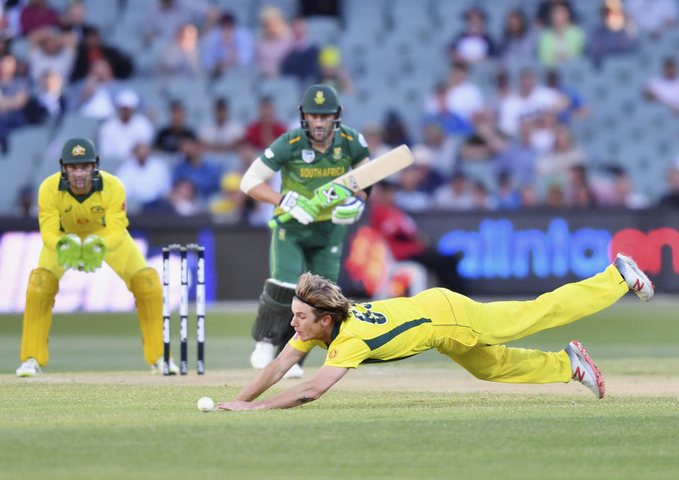 Adam Zampa, front, of Australia fields the ball off his own bowling to Faf du Plessis, center, of South Africa during their second One-Day International cricket match in Adelaide, Friday, Nov. 9, 2018. (David Mariuz/AAP Image via AP)