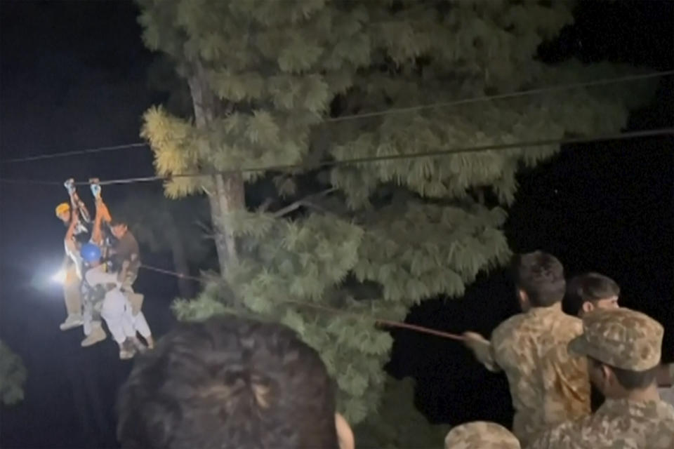 In this image made from video provided by Pakistan Rescue Military, Pakistani military and local rescue workers bringing last people from cable car to safety using ropes and harnesses, in Battagram district in Khyber Pakhtunkhwa province, Pakistan, Tuesday, Aug. 22, 2023. Army commandos using helicopters and a makeshift chairlift rescued eight people from a broken cable car as it dangled hundreds of meters above a canyon in Pakistan. Authorities said the rescues were completed late Tuesday in a remote, mountainous part of the country. (Pakistan Rescue Military via AP)