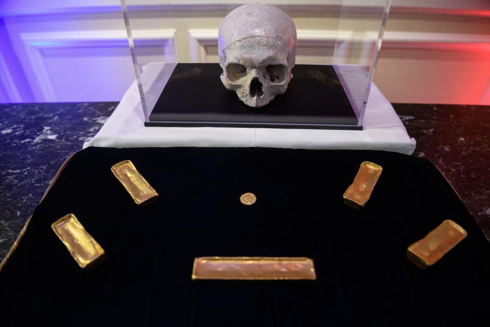 Artifacts are displayed during a ceremony marking the restitution of cultural property from the U.S. to France at the ambassador's residence in Washington, D.C., on March 2, 2022. The items include five gold ingots from the Prince de Conty, which sank near the Breton coast in 1746, a gold coin from the third century discovered in 1985 of Corsica's Gulf of Lava, and a skull from the Paris catacombs. / Credit: NICHOLAS KAMM/AFP via Getty Images