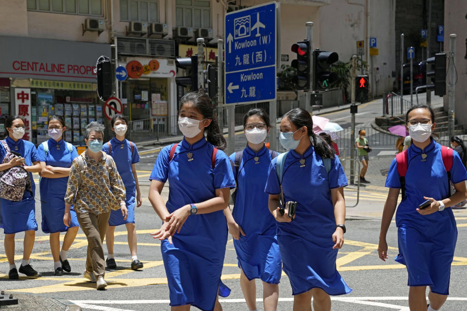 Students wearing face masks to prevent the spread of the coronavirus, walk across a street in Hong Kong, Thursday, June 10, 2021. Government officials said Thursday that they will expand the vaccination drive to about 240,000 children from 12 to 15 years old starting Friday, joining other countries such as Singapore and the U.S. that have started vaccinating children. (AP Photo/Kin Cheung)