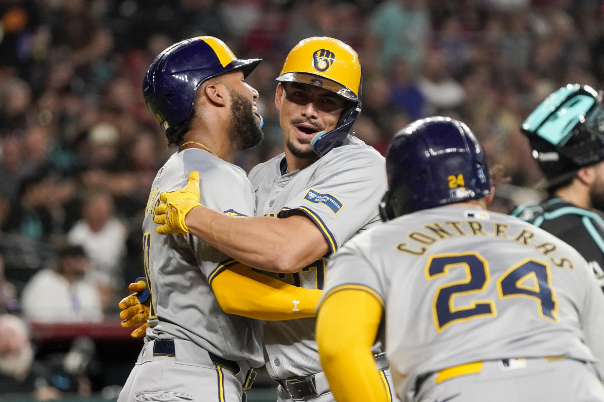 Milwaukee Brewers' Willy Adames, center, is congratulated by Jackson Chourio, left, and William Contreras (24) after hitting a grand slam against the Arizona Diamondbacks during the second inning of a baseball game, Saturday, Sept. 14, 2024, in Phoenix. (AP Photo/Darryl Webb)