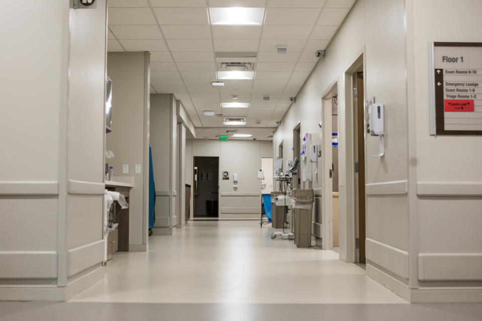 A clean, well-lit hospital corridor with medical equipment and rooms along the sides