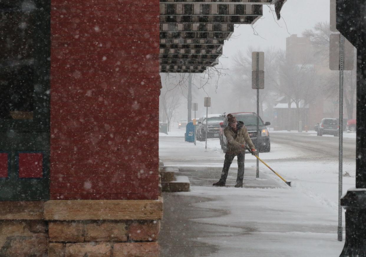 Riley Meister, of Meister Mowing, clears the sidewalks in front of the Dacotah Prairie Museum Tuesday. Snow has been falling off and on throughout the day Tuesday and is expected to continue Wednesday.