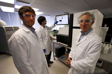 Technician Mike Lattari (rear) works on a genetic sequencing machine as Alan Shuldiner (R) and Aris Baras, co-heads of the Regeneron Genetics Center, pose for a photo at a Regeneron Pharmaceuticals Inc. laboratory at the biotechnology company's headquarters in Tarrytown, New York March 24, 2015. REUTERS/Mike Segar