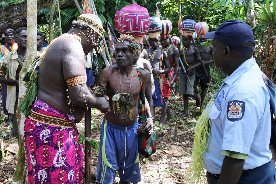 In this Nov. 30, 2019, photo released by Bougainville Referendum Commission (BRC), a BRC returning officer, left, leads an Upe man to men-only polling station in the Bougainville referendum in Teau, Bougainville, Papua New Guinea. All across the Pacific region of Bougainville, people have voted in a historic referendum to decide if they want to become the world’s newest nation by gaining independence from Papua New Guinea. (Jeremy Miller/BRC via AP)