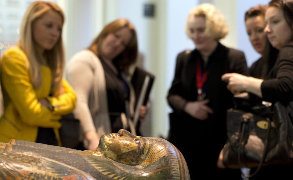 Members of the media stand around the Mummy of Tamut, a temple singer around 900 BC, during a press conference at the British Museum in London, Wednesday April 9, 2014. Scientists at the British Museum have used CT scans and volume graphics software to go beneath the bandages, revealing the skin, bones, internal organs, and in one case a brain-scooping rod left inside a skull by embalmers. The results are going on display in an exhibition which sets eight of the museum's mummies alongside detailed 3-D images of their insides. (AP Photo/Alastair Grant)