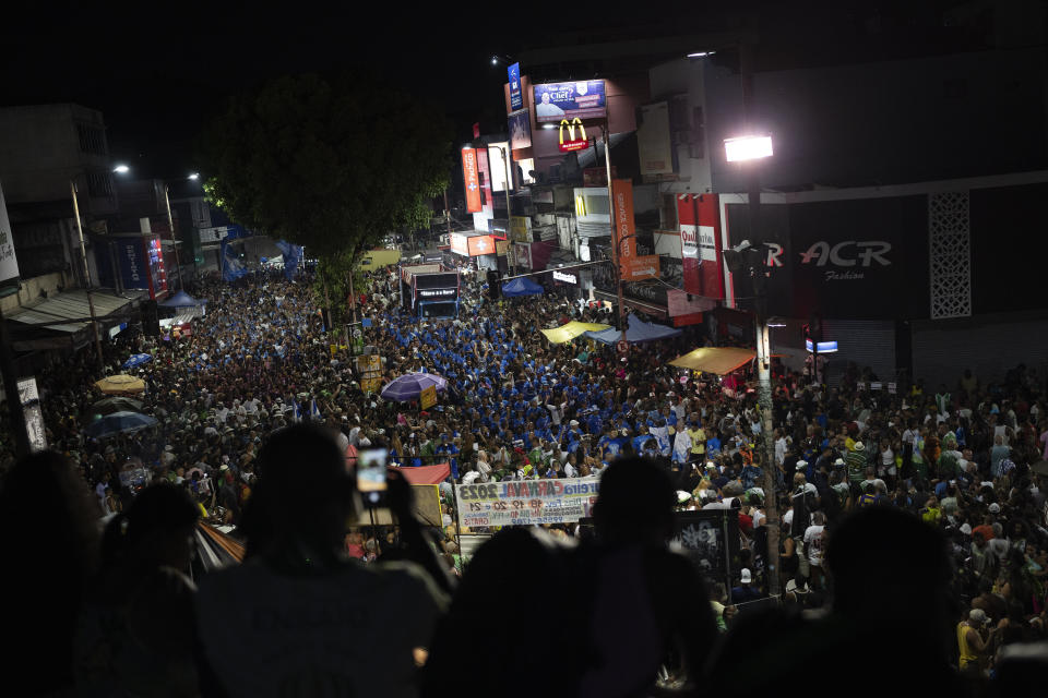 People watch from a bridge the rehearsal of the Imperio Serrano and Beija Flor samba schools in the streets ahead of Rio de Janeiro's Carnival Parade, in Rio de Janeiro, Brazil, Tuesday, Jan. 31, 2023. (AP Photo/Silvia Izquierdo)