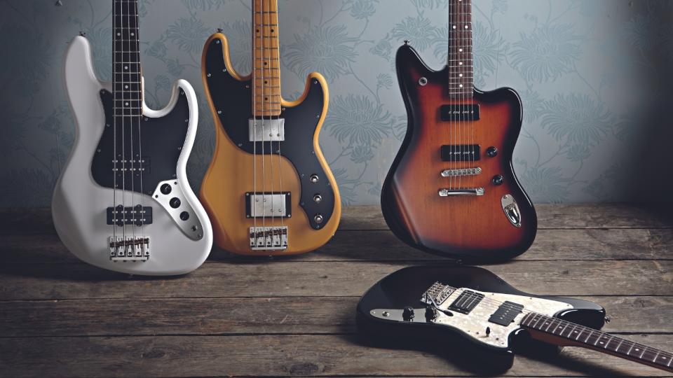 A group of Fender guitars leaning against a wall, with one lying on the wooden floor