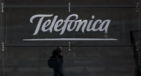 A reflection of a man talking on his phone is seen outside Telefonica's flagship store in central Madrid, Spain, April 28, 2015. REUTERS/Sergio Perez