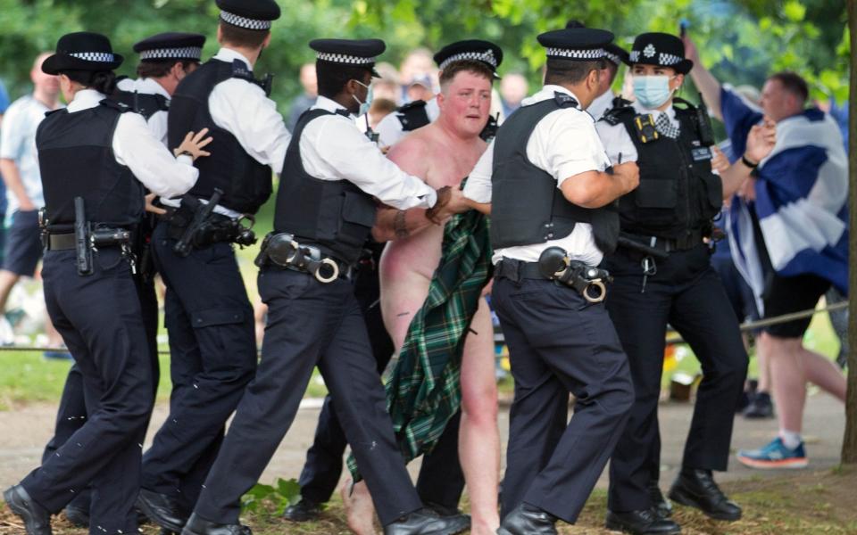 A de-kilted man is led away by police officers - Martyn Wheatley/i-Images