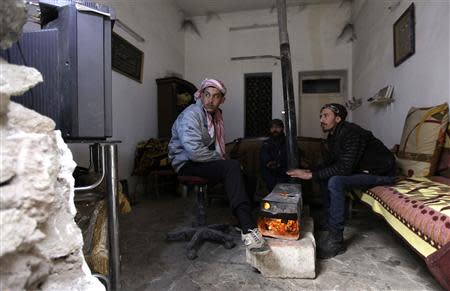 Free Syrian Army fighters warm themselves around a heater inside a room in Deir al-Zor, eastern Syria, December 12, 2013. REUTERS/Khalil Ashawi