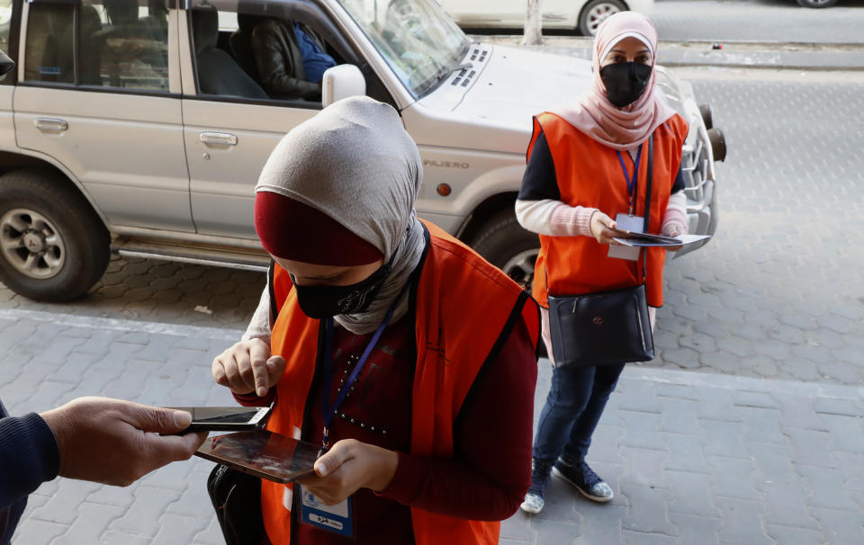 Members of Central Elections Commission's filed teams register a local resident to the electoral roll, at the main road of Gaza City, Feb. 10, 2021. Palestinian poll workers fanned out across the Gaza Strip on Wednesday, where they found voters eager to register ahead of elections that could serve as the first referendum on Hamas' rule since the militant group seized power more than a decade ago. (AP Photo/Adel Hana)