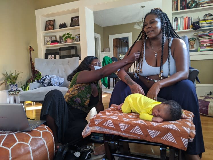 Midwife Kiki Jordan examines TaNefer Camara during a routine postnatal visit. about a week after the birth of her son, Esangu.