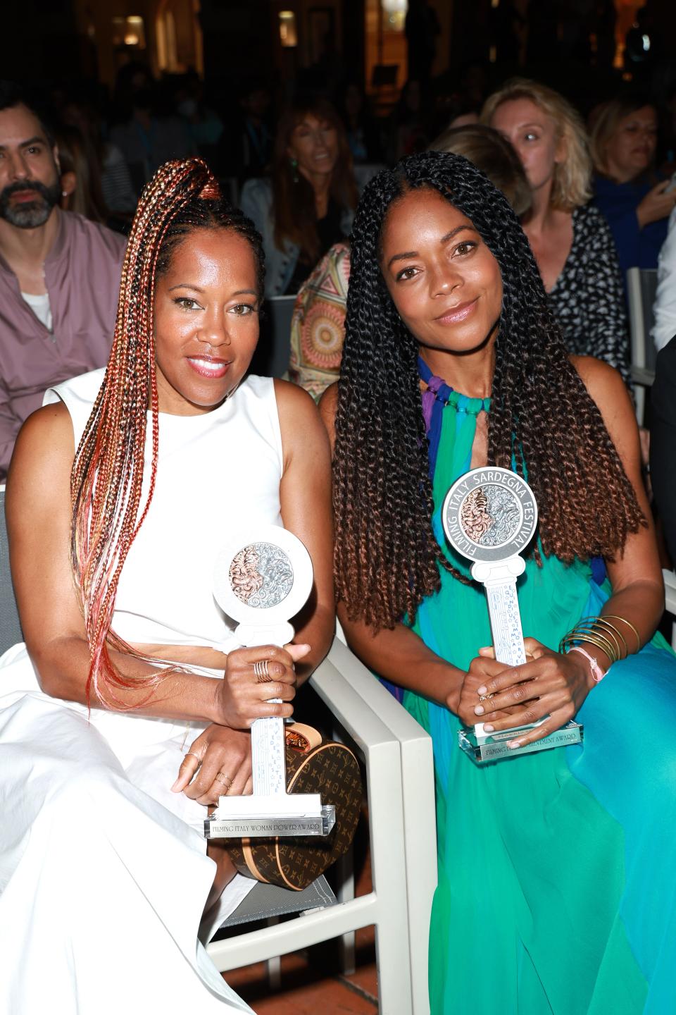 Regina King in a white gown sitting next to Naomie Harris in a turquoise gown holding the Women Power Award