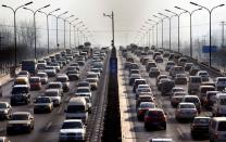 FILE PHOTO: Cars drive along a main road in central Beijing