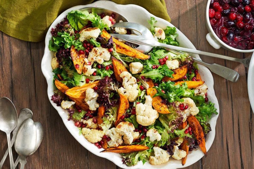 thanksgiving salad with charred cauliflower and sweet potato wedges in a white serving dish