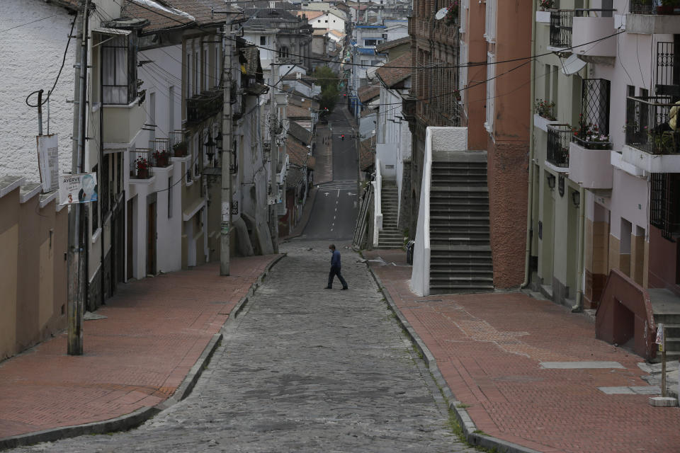 A downtown resident crosses a street free of pedestrians and traffic as a result of new lockdown restrictions due to the increase in COVID-19 infections, in Quito, Ecuador, Saturday, April 24, 2021. (AP Photo/Dolores Ochoa)
