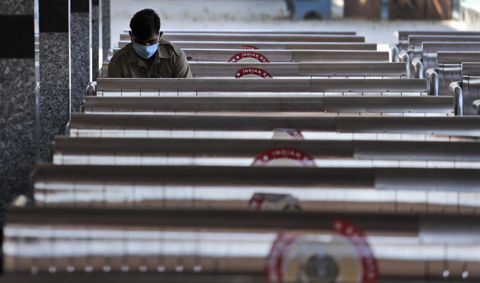 A railway employee sits in the corner of a deserted railway station during a 21 day lockdown to control the spread of coronavirus in New Delhi, India, Thursday, April 2, 2020. The new coronavirus causes mild or moderate symptoms for most people, but for some, especially older adults and people with existing health problems, it can cause more severe illness or death. (AP Photo/Manish Swarup)