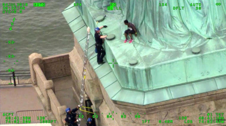 FILE- In this July 4, 2018, frame from video provided by the New York City Police Department, members of the NYPD Emergency Service Unit work to safely remove Therese Okoumou, a protester who climbed onto the Statue of Liberty and was charged with misdemeanor trespassing and disorderly conduct. Okoumou who climbed the base of the Statue of Liberty to protest the separation of families at the Mexican border has been sentenced to five years' probation and 200 hours of community service. (NYPD via AP, FILE)