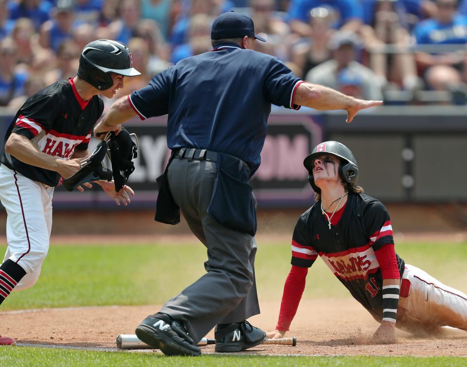 Hiland baserunner Alec Weaver, bottom, looks to home plate umpire Jay Moran for the call after scoring a run against Russia during the fifth inning of the OHSAA Division IV state championship baseball game at Canal Park, Saturday, June 10, 2023, in Akron, Ohio.