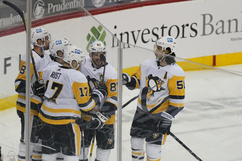 Pittsburgh Penguins center Sidney Crosby (87), and teammates celebrate with right wing Bryan Rust (17) after he scored a goal during the second period of an NHL hockey game against the New Jersey Devils, Sunday, April 11, 2021, in Newark, N.J. (AP Photo/Kathy Willens)