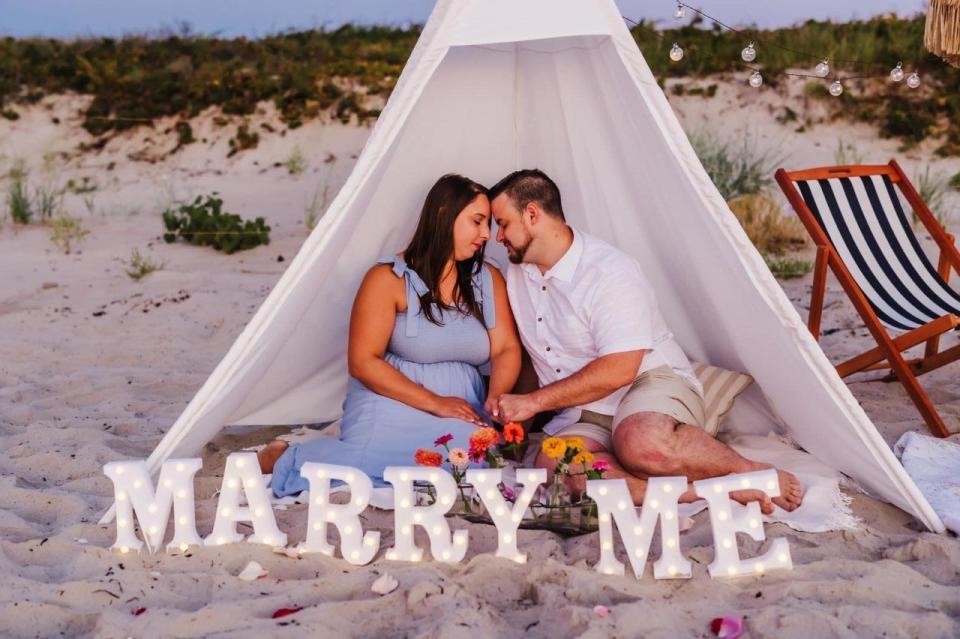 A young couple enjoys a moment at a picnic site that business owner Megan Petrus, of Sunrise Picnics, set up on Ogunquit Beach for the occasion of their wedding engagement.